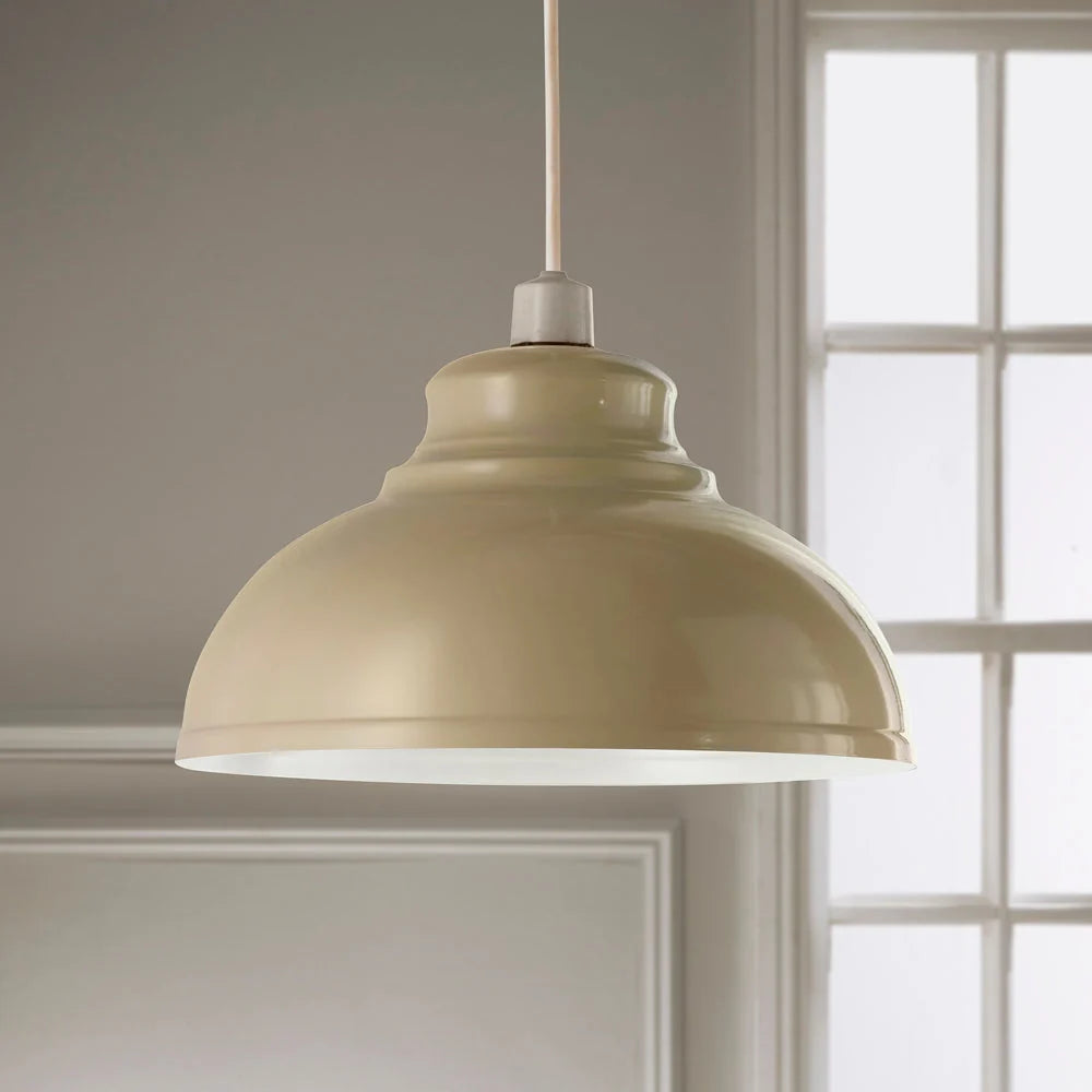 A dome-shaped pendant light with a glossy cream finish hanging from a cord in front of a softly blurred window and wall.
